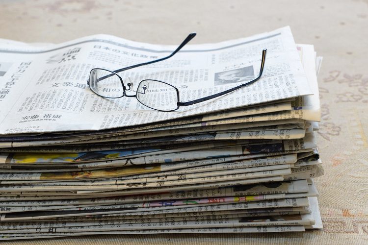 山積みの新聞紙と眼鏡