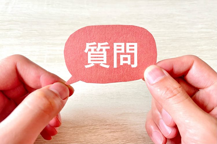 質問と書かれた吹き出しを持つ人の手